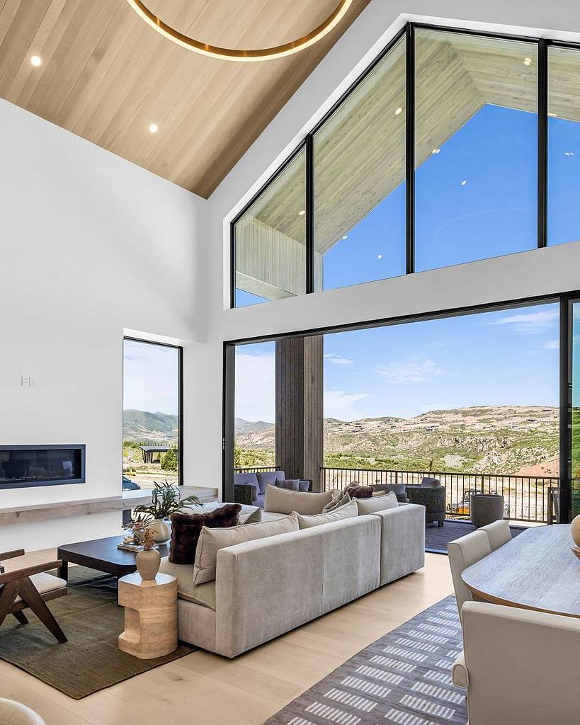 Great room with soaring gabled windows, fireplace, and mountain views at The Skyfall Residence, a luxury home rental near Deer Valley